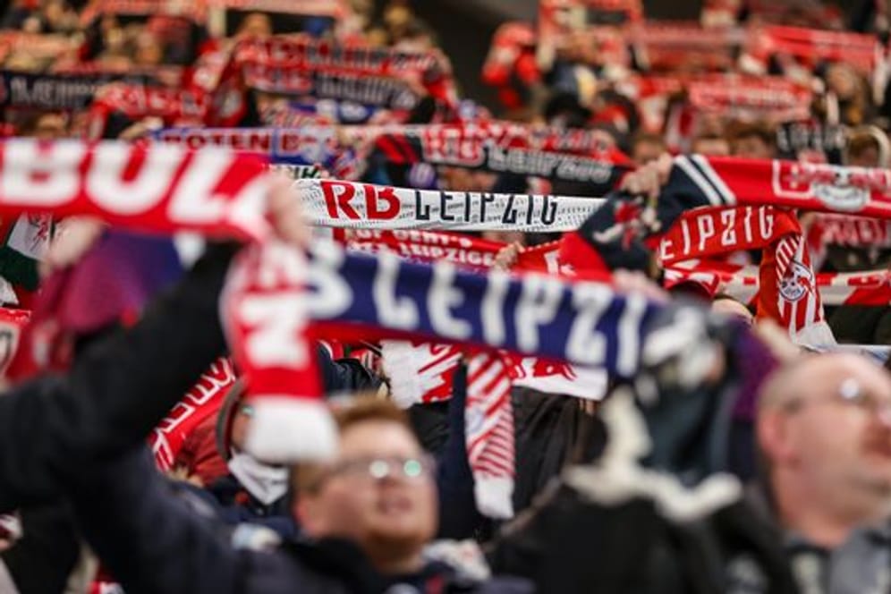 Fans von RB Leipzig halten ihre Fanschals in die Höhe.