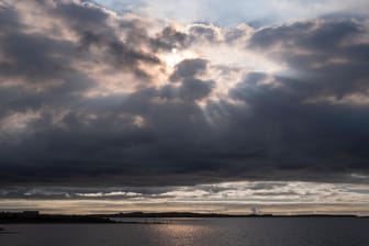 Sonnenstrahlen durchbrechen die dunklen Wolken (Symbolbild): Im Norden folgt auf Gewitter Sonnenschein und sommerliche Temperaturen.