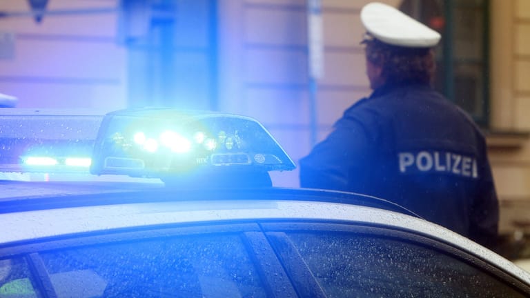 Ein Polizist vor einem Einsatzwagen mit Blaulicht (Symbolbild): Ein Anwohner hatte die Beamten alarmiert.