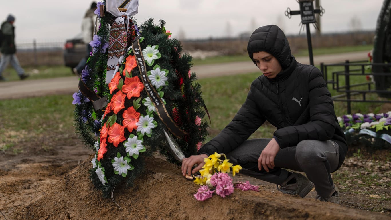 Der 15-jährige Jura Nechyporenko am Grab seines Vaters in Butscha: Der Junge überlebte einen Mordversuch durch russische Soldaten, sein Vater nicht.