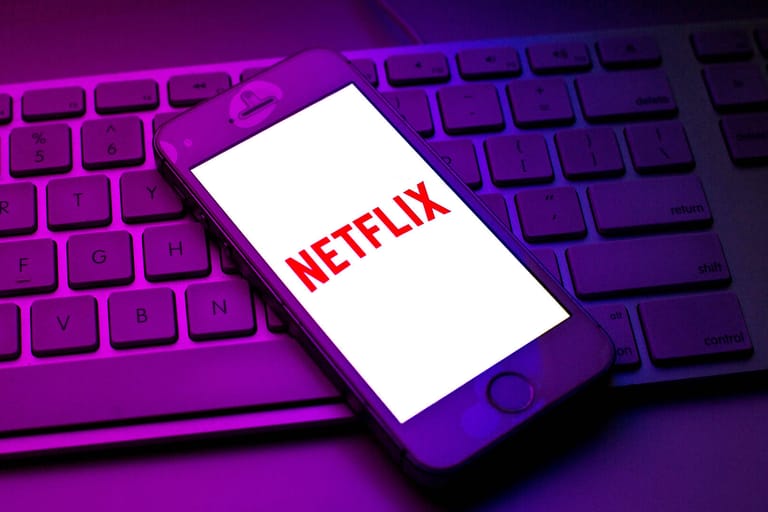 Eine Person vor einer Bildschirmwand mit dem Netflix-Logo (Symbolbild): Netflix kämpft mit sinkenden Abozahlen und einer wachsenden Konkurrenz.