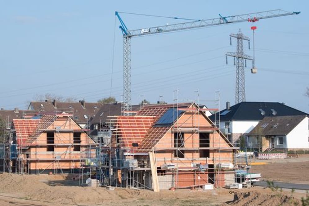 Einfamilienhäuser stehen im Rohbau in einem Neubaugebiet.