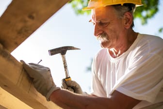 Älterer Dachdecker bei der Arbeit (Symbolbild): Gerade in körperlich anstrengenden Berufen erreichen viele Beschäftigte die Regelaltersgrenze für die Rente gar nicht.