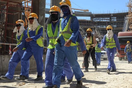 Ausländische Bauarbeiter verlassen eine Baustelle.