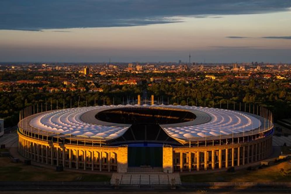 Die untergehende Sonne scheint auf das Olympiastadion in Berlin.