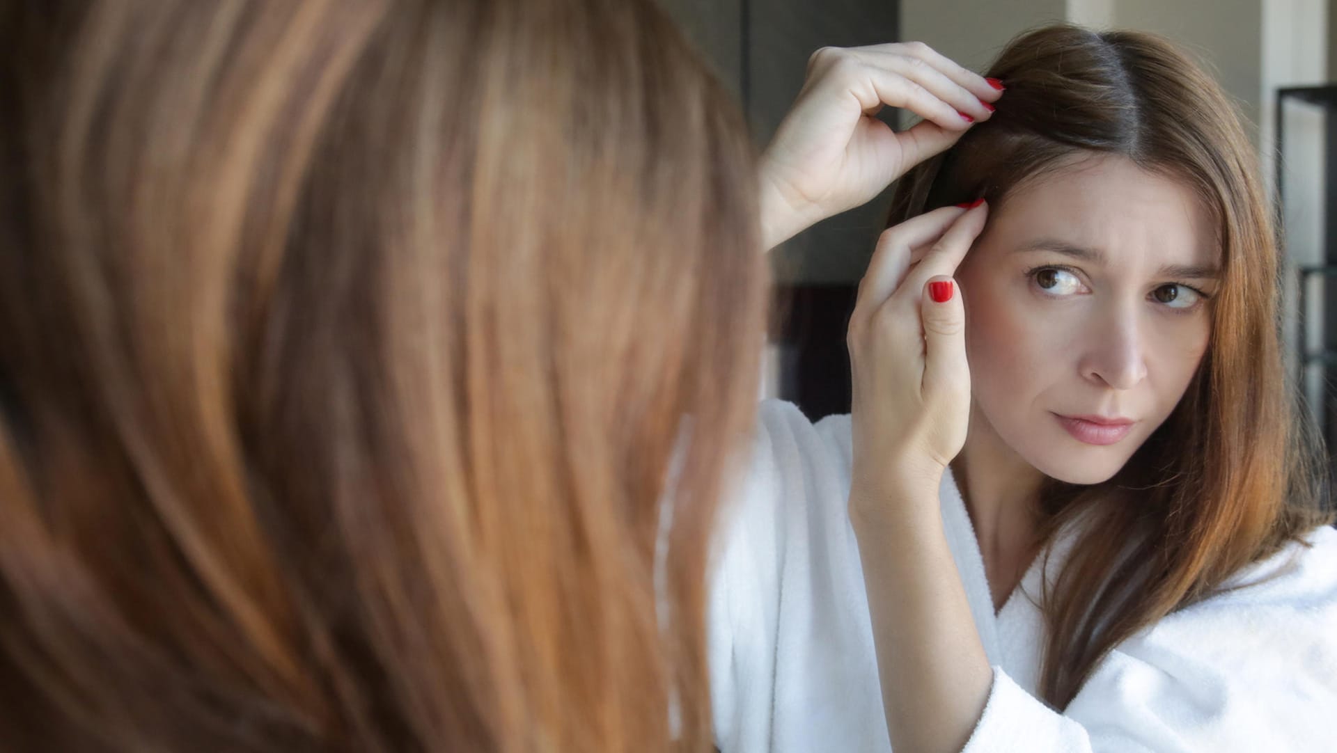 Junge Frau in Sorge wegen Haarausfall: Frischgebackene Mütter klagen nach der Geburt ihres Kindes oft über Haarausfall. Schuld daran ist die hormonelle Umstellung.