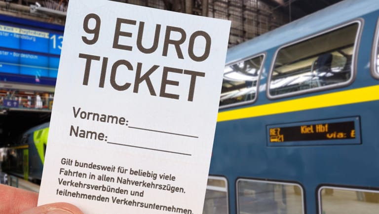 Eine Hand hält ein weißes 9-Euro-Ticket hoch (Symbolbild): Für drei Monate können Bürger alle Züge und Busse im Regional- und Nahverkehr nutzen.