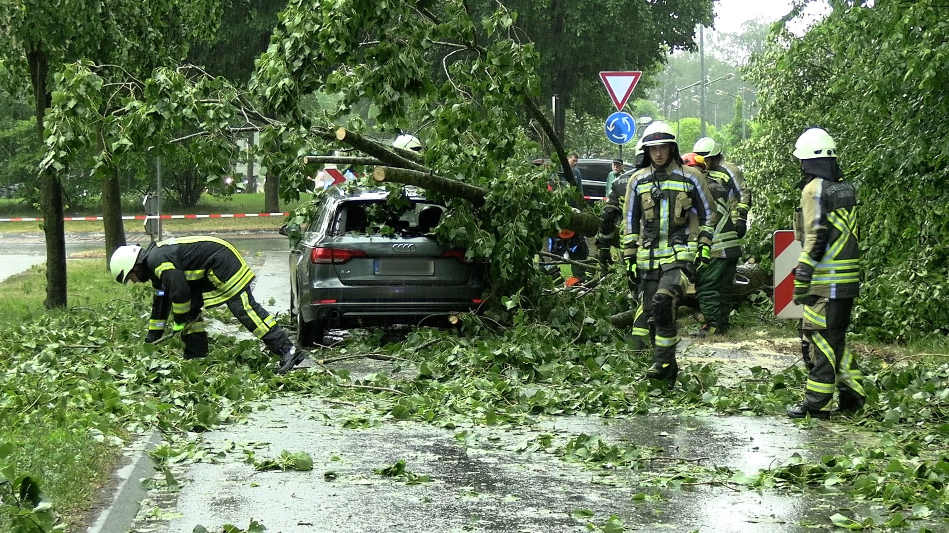 Feuerwehrleute beseitigen einen durch Gewitterböen umgestürzten Baum von einem Auto in Nordrhein-Westfalen: Die Feuerwehr musste mehrmals wegen Unwetterschäden ausrücken.