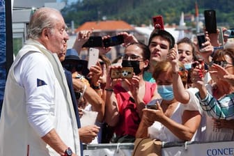 Juan Carlos (l), Altkönig von Spanien, spricht mit Schaulustigen vor einem Empfang in einem Nautikclub vor einer Segelveranstaltung in Sanxenxo.