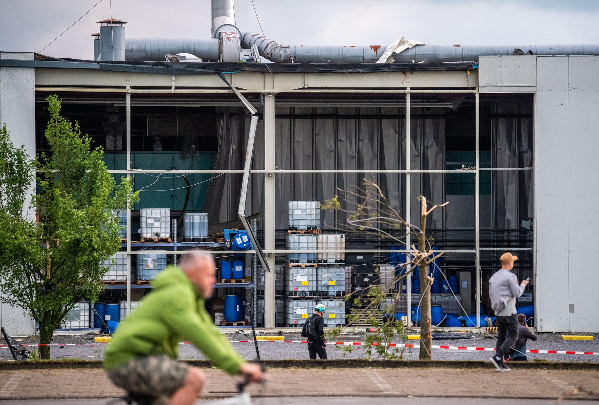 Paderborn: Personen machen Fotos von einer Fabrik, aus der der Sturm eine Wand herausgerissen hat.