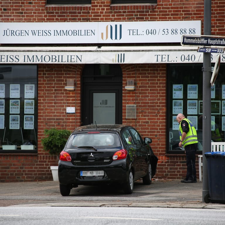 Ein Polizist am Unfallort: In Hummelsbüttel ist ein Mann mit seinem Wagen gegen eine Hauswand gefahren.