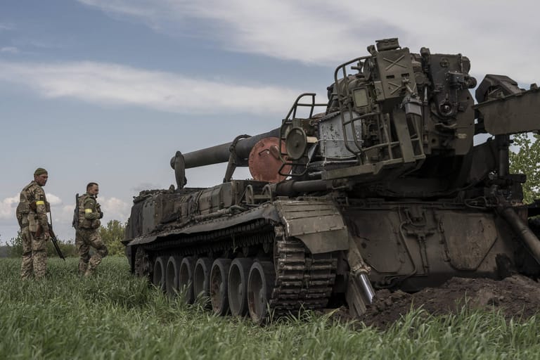 Ukrainische Soldaten stehen in der Region Kiew vor einem zerstörten russischen Panzer.