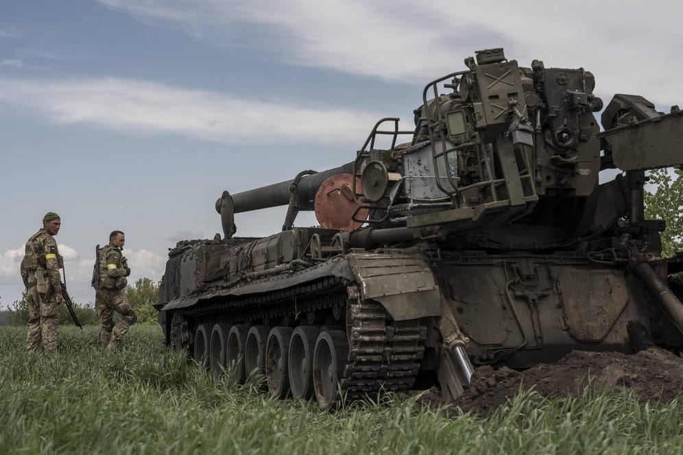 Ukrainische Soldaten stehen in der Region Kiew vor einem zerstörten russischen Panzer.