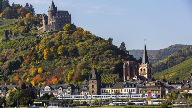 Ein Zug passiert den Weinort Bacharach und die Burg Stahleck: Das Obere Mittelrheintal gilt seit 2002 als Unesco Welterbe.