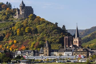 Ein Zug passiert den Weinort Bacharach und die Burg Stahleck: Das Obere Mittelrheintal gilt seit 2002 als Unesco Welterbe.