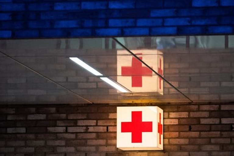 Ein rotes Kreuz vor einer Notaufnahme (Symbolbild): Nach dem Stromunfall im Münchner Bahnhof Trudering sind zwei Verletzte im künstlichen Koma.