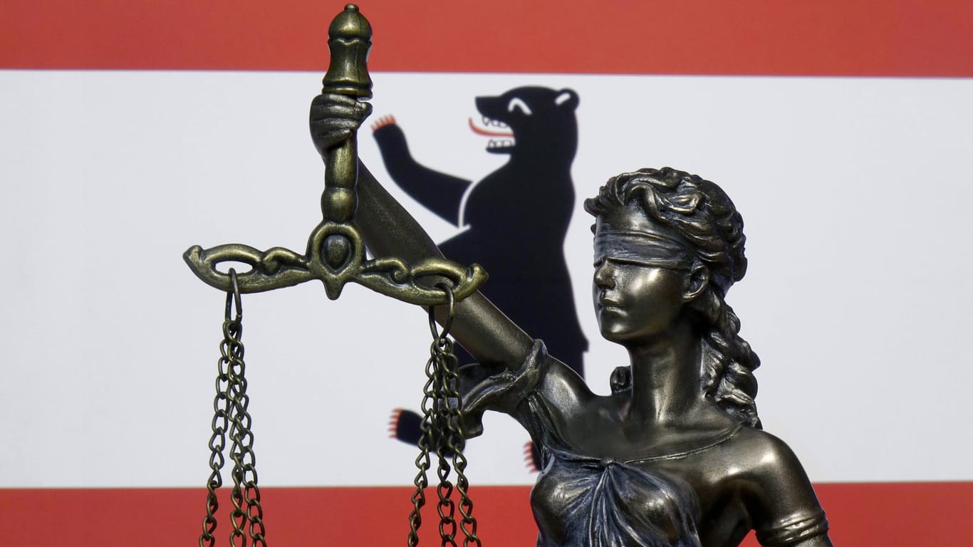 Eine Figur von Justitia steht vor der Länderfahne von Berlin (Symbolbild): Das Arbeitsgericht urteilte, dass ein gefälschter Genesenennachweis eine Kündigung rechtfertigt.