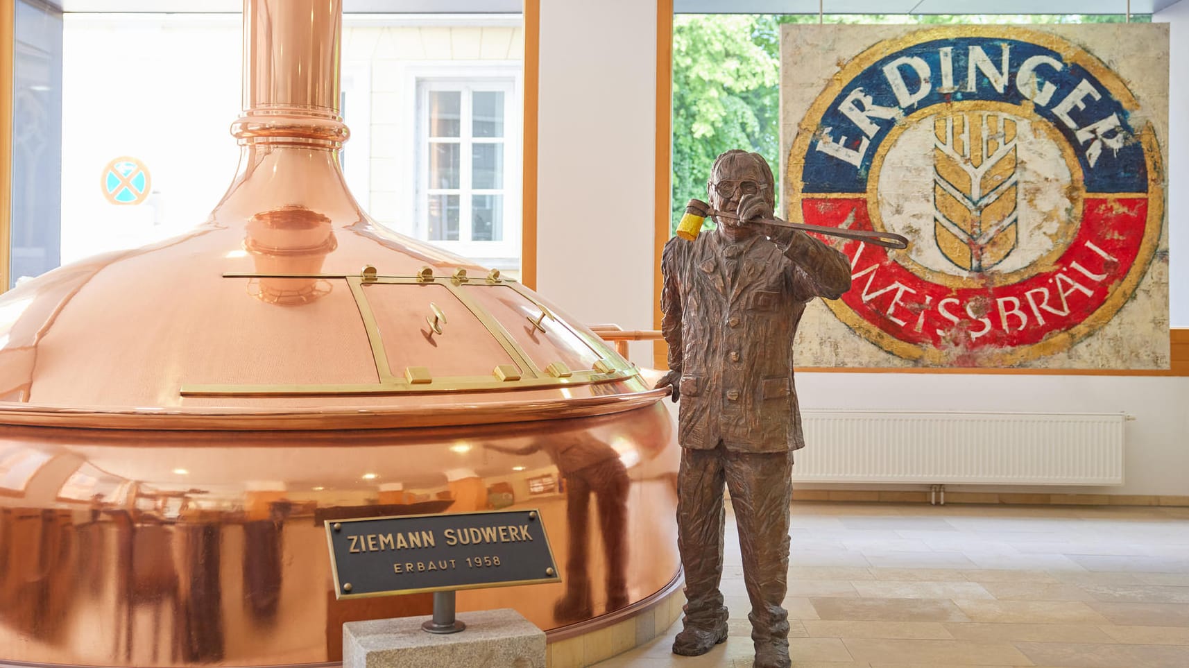 Eine Statue des Erdinger-Inhabers Werner Brombach steht im Stammhaus der Brauerei gleich neben einem alten Braukessel.