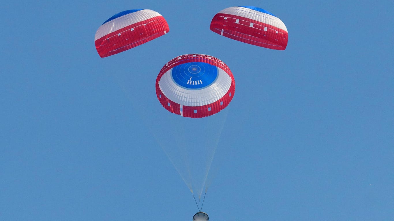 Ein Bild der Nasa zeigt die Starliner-Kapsel an Fallschirmen hängend.
