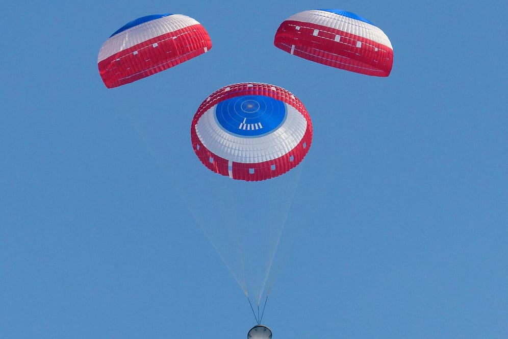 Ein Bild der Nasa zeigt die Starliner-Kapsel an Fallschirmen hängend.