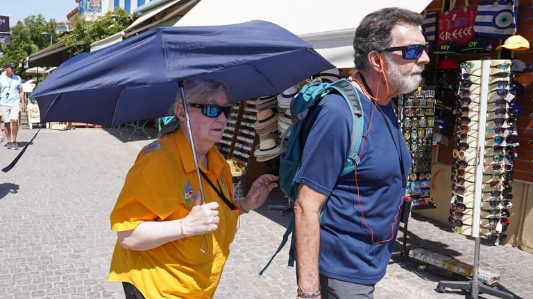 Touristen mit Sonnenschirm in Athen: In den kommenden Tagen soll es besonders heiß werden.