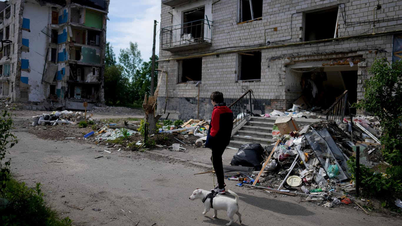 Ukraine-Krieg: Ein Mann geht mit seinem Hund vor einem von Granaten zerstörten Gebäude in Borodjanka bei Kiew spazieren