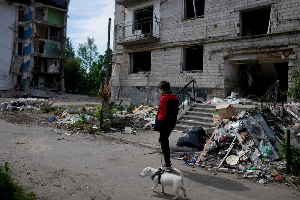 Ukraine-Krieg: Ein Mann geht mit seinem Hund vor einem von Granaten zerstörten Gebäude in Borodjanka bei Kiew spazieren