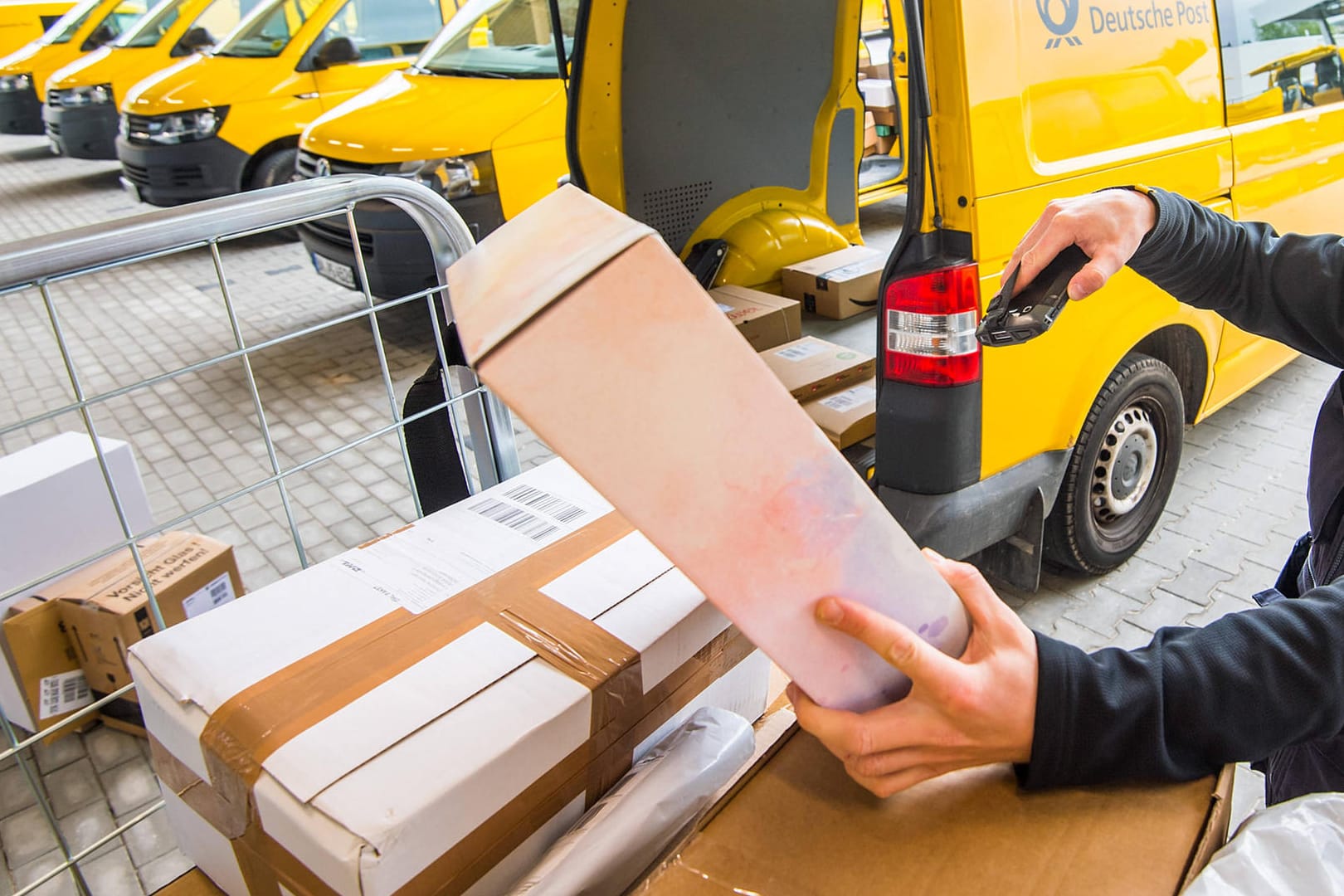 DHL-Mitarbeiter scannt Pakete (Symbolbild): Viele Händler verlangen bisher keine Rücksendegebühren. Entsprechend viel Arbeit haben Lieferdienste mit Retouren.ete mit einem DHL-Mitarbeiter scannt Pakete (Symbolbild): Viele Händler verlangen bisher keine Rücksendegebühren. Entsprechend viel Arbeit haben Lieferdienste mit Retouren.ete mit einem