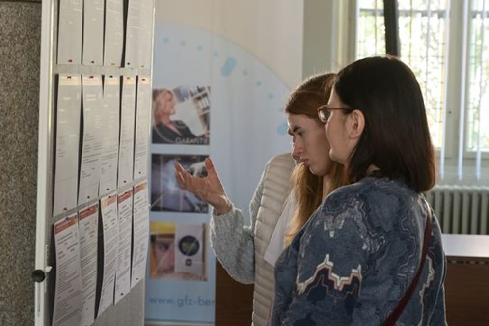 Frauen, die aus der Ukraine geflüchtet sind, informieren sich an einer Tafel über Arbeitsangebote.