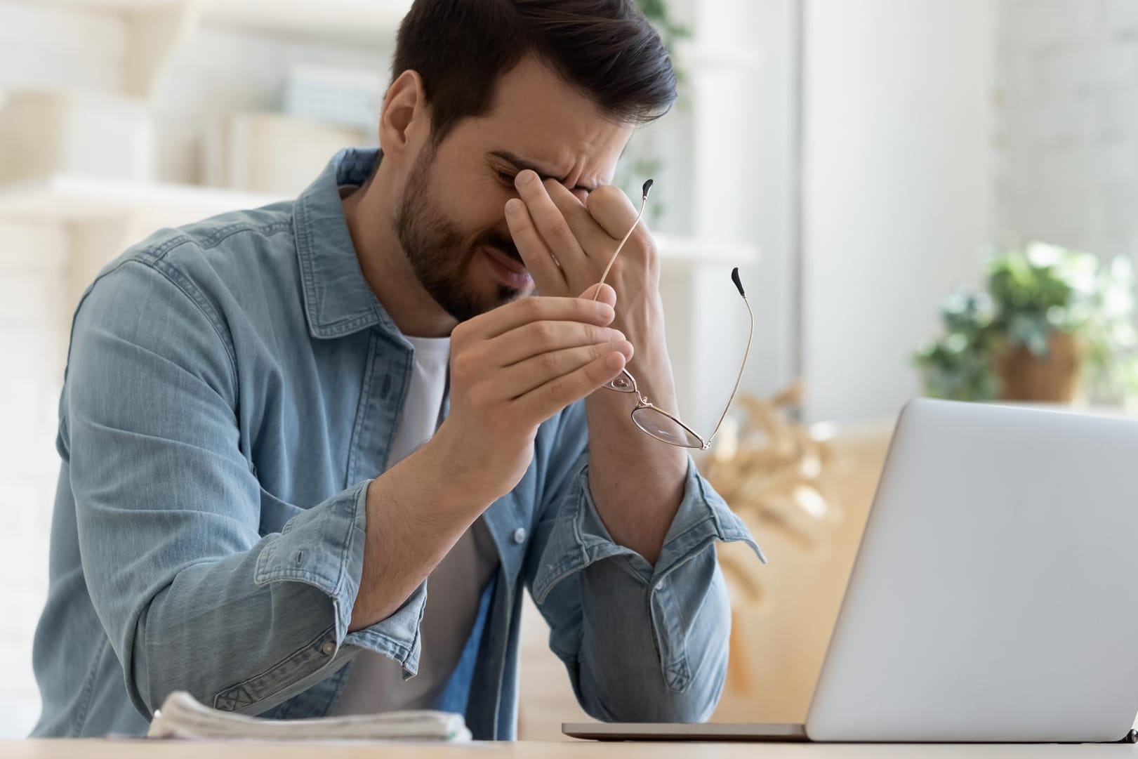 Mann am Laptop reibt sich die Augen.