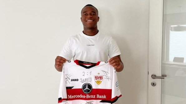 Youssufa Moukoko zeigt das VfB-Trikot mit allen Unterschriften der dankbaren Spieler.