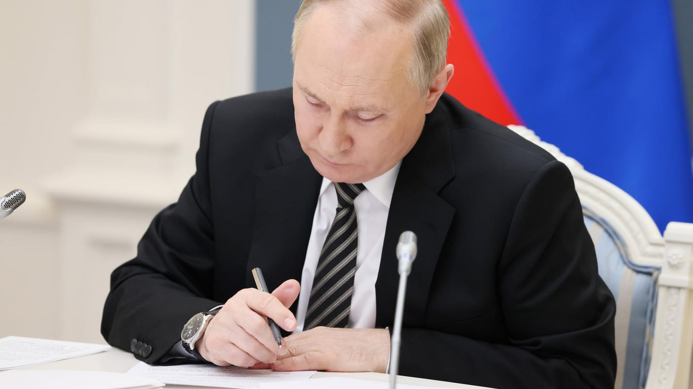 Wladimir Putin schaut auf Dokumente (Archivbild): Der russische Präsident will über Getreideexporte verhandeln.