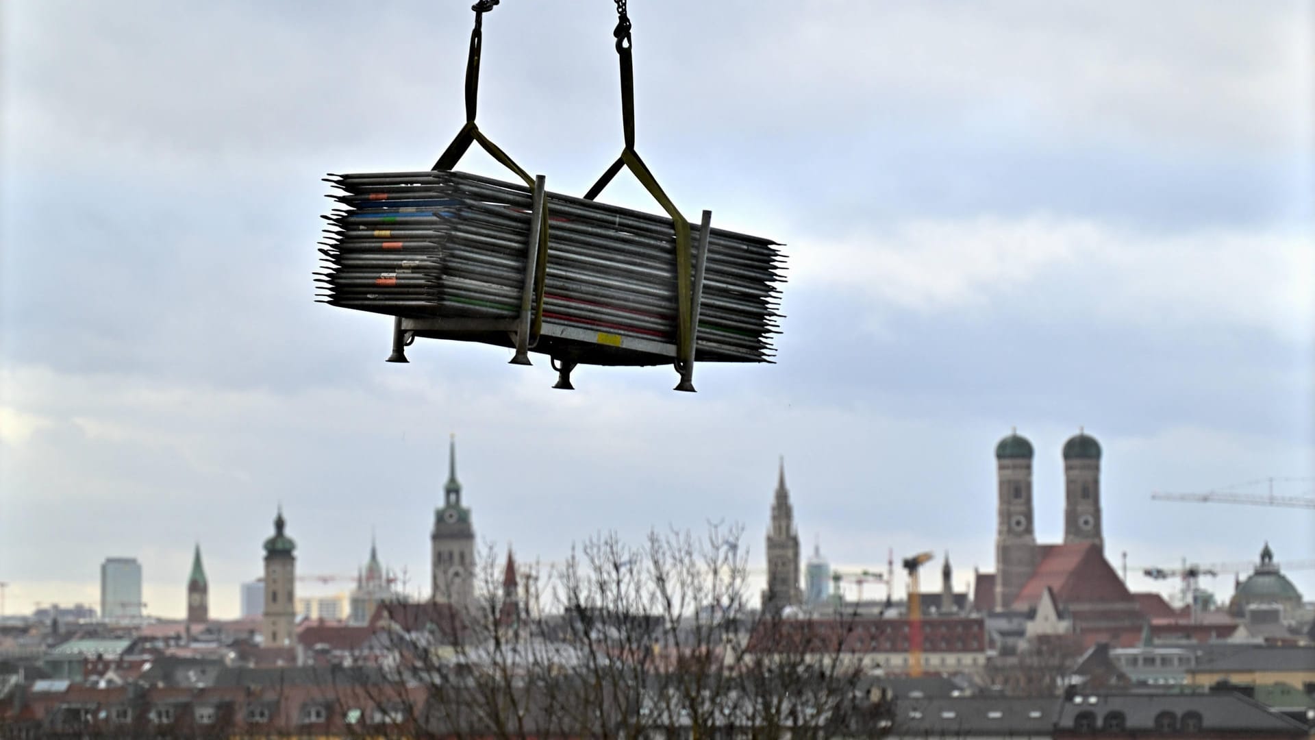 Baumaterial an einem Kran vor der Kulisse Münchens (Symbolbild): Die bayerische Landeshauptstadt ist zu Investitionen gezwungen, und damit auch zum Bauen.