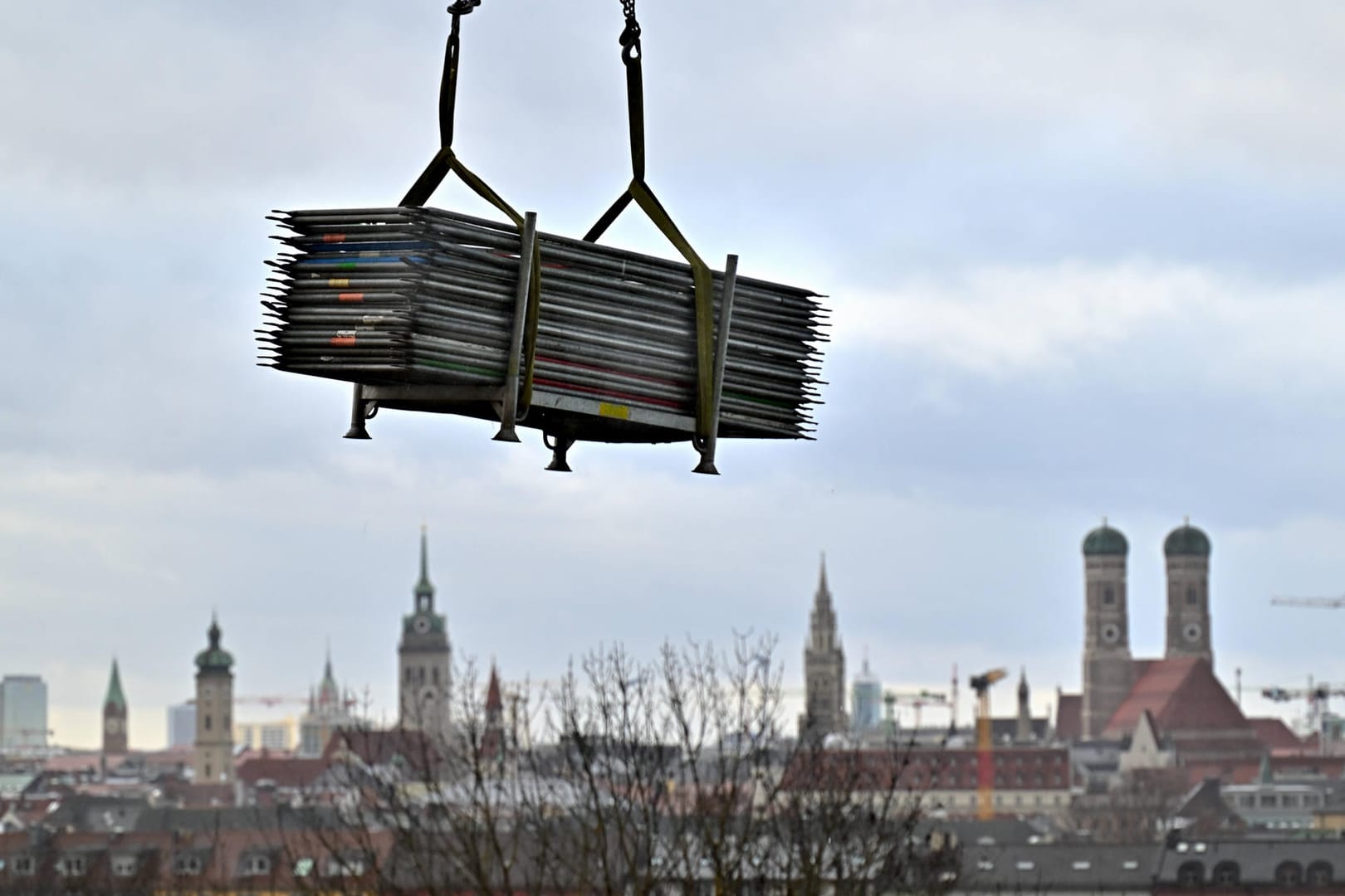 Baumaterial an einem Kran vor der Kulisse Münchens (Symbolbild): Die bayerische Landeshauptstadt ist zu Investitionen gezwungen, und damit auch zum Bauen.