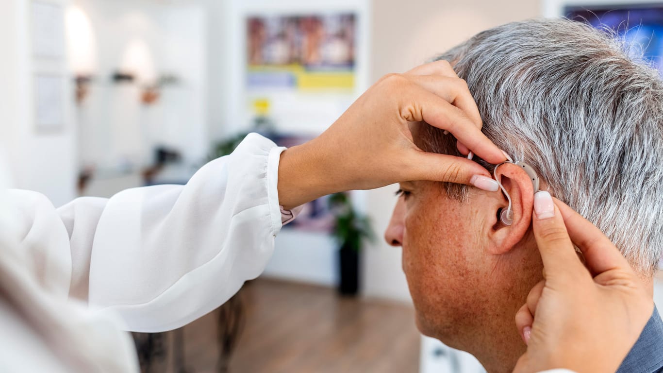 Älteren Mann wird Hörgerät eingesetzt: Ist das Hörvermögen so beeinträchtigt, dass es den Alltag erschwert, kann ein Hörgerät helfen.