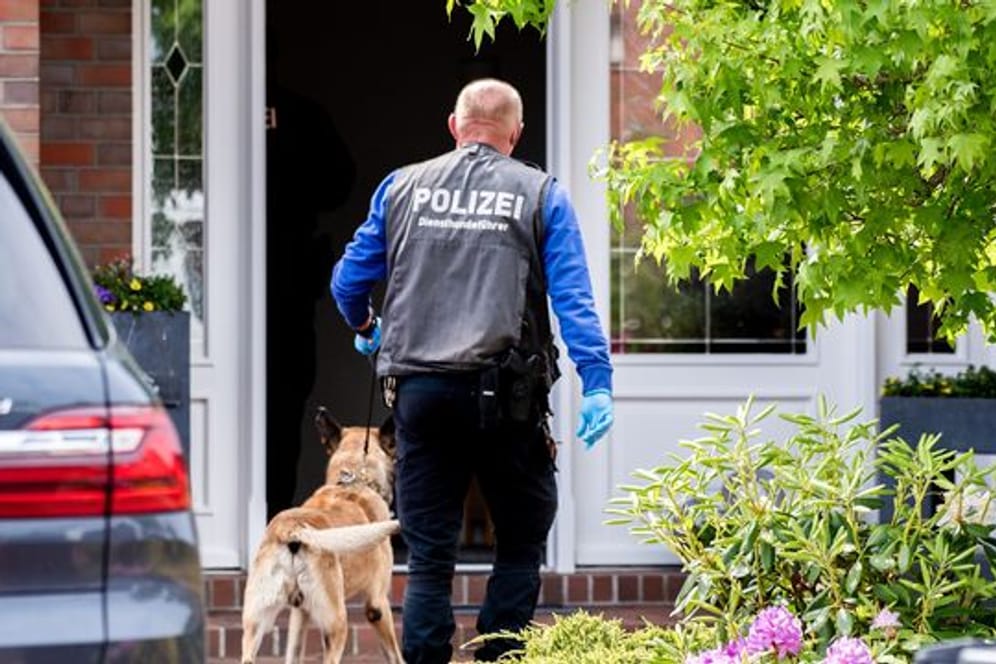 Ein Diensthundeführer der Polizei geht mit einem Spürhund zu einem Wohnhaus in Wiesmoor.