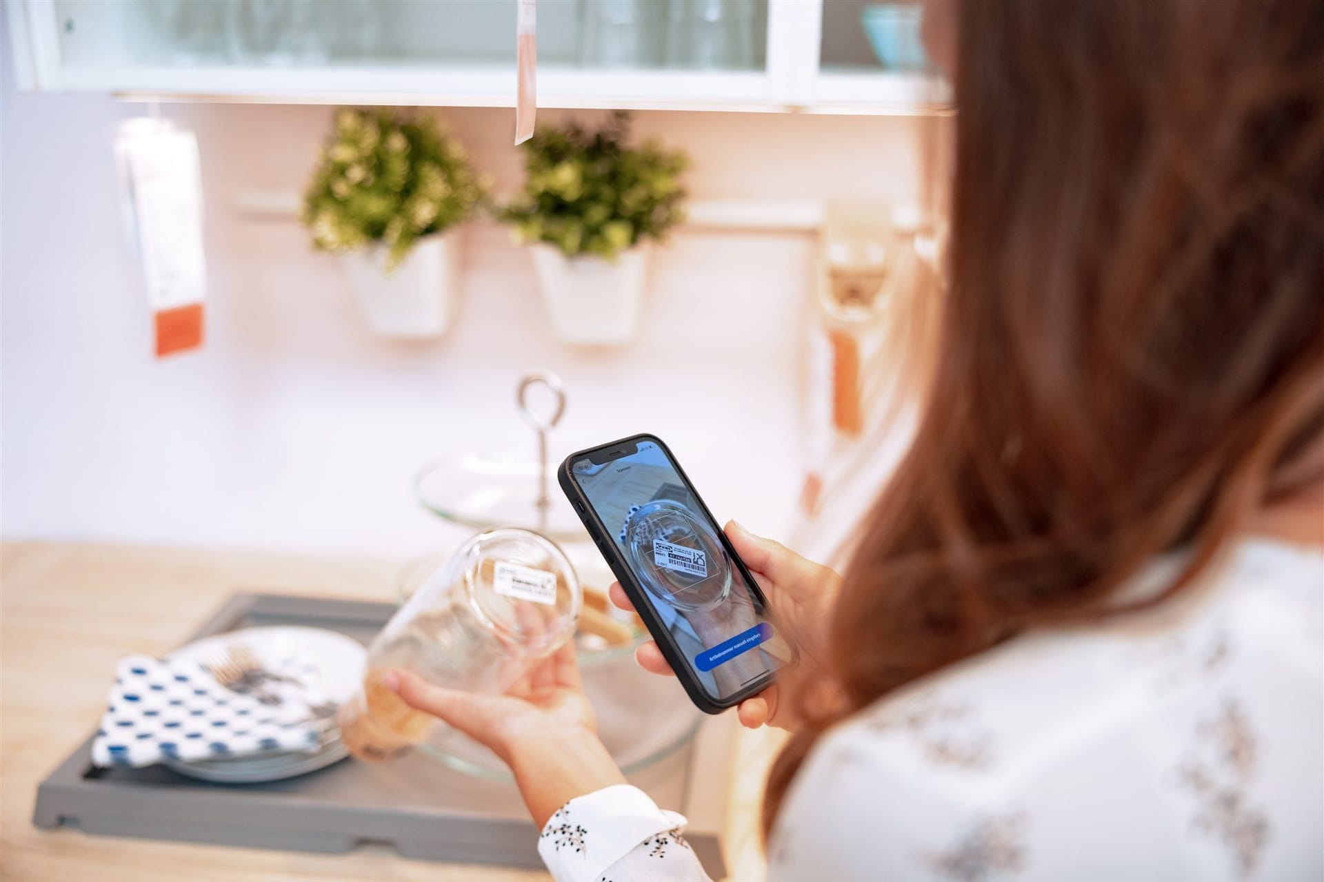 Frau mit Smartphone: Mit Shop & Go werden Artikel gescannt, bevor sie in den Einkaufswagen gelegt werden.