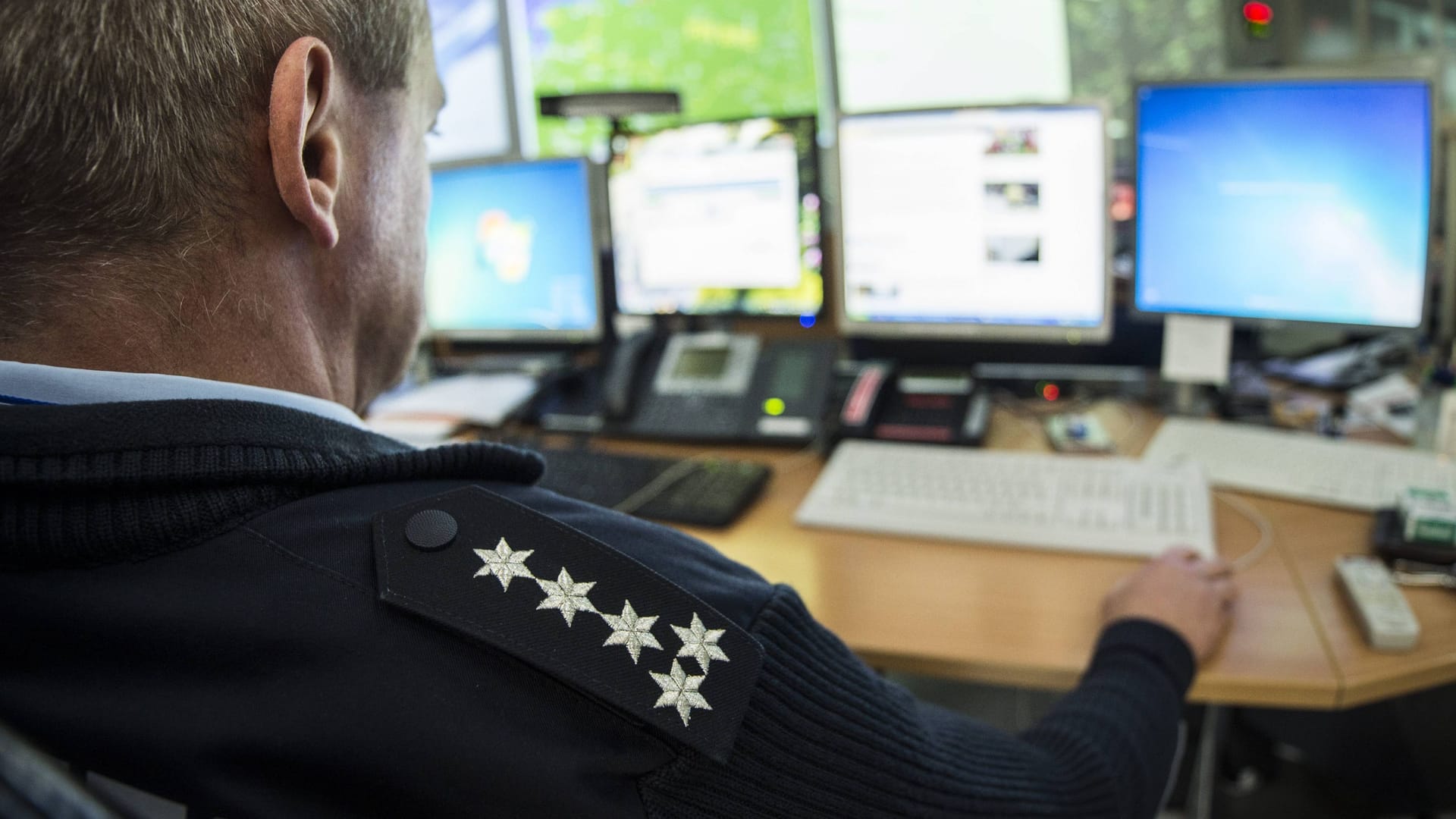 Ein Polizist sitzt vor dem Computer (Symbolbild): Die ausführliche Polizeidatenbank Poliks wird von Beamtinnen und Beamten immer wieder für private Zwecke missbraucht.