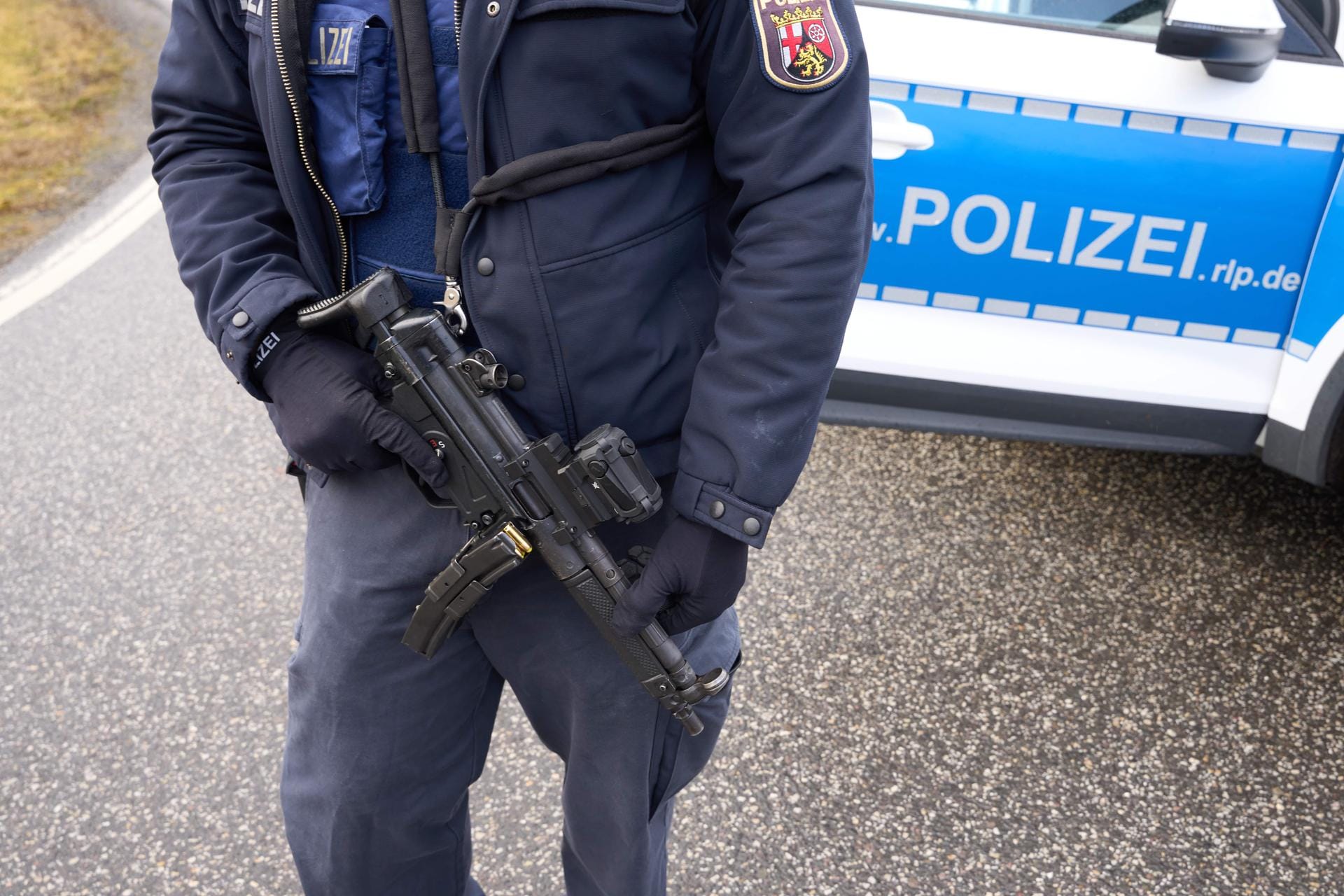 Ein schwer bewaffneter Beamter bewacht den Tatort in Rheinland-Pfalz: Im Landkreis Kusel ist eine Verkehrskontrolle eskaliert. Eine Polizistin und ein Polizist starben.