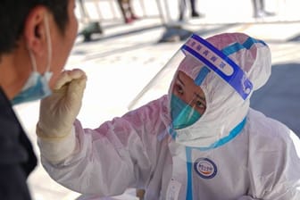 Eine medizinische Angestellte testet einen Anwohner in Pekings Bezirk Daxing auf das Coronavirus.