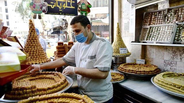 Ein Konditor arrangiert Baklava in einem Geschäft in Syrien. Ein Konditor arrangiert Baklava in einem Geschäft in Syrien.