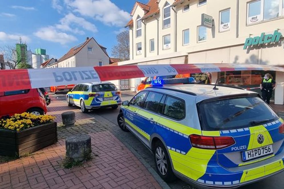 Einsatzfahrzeuge der Polizei stehen am abgesperrten Tatort im niedersächsischen Burgdorf, wo eine Frau von einem Mann mit einem Messer getötet wurde.