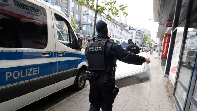 Ein Polizist trägt eine Kiste aus einem Gebäude, die die Polizei bei einer Razzia gegen Clankriminalität fand. Ein Polizist trägt eine Kiste aus einem Gebäude, die die Polizei bei einer Razzia gegen Clankriminalität fand.