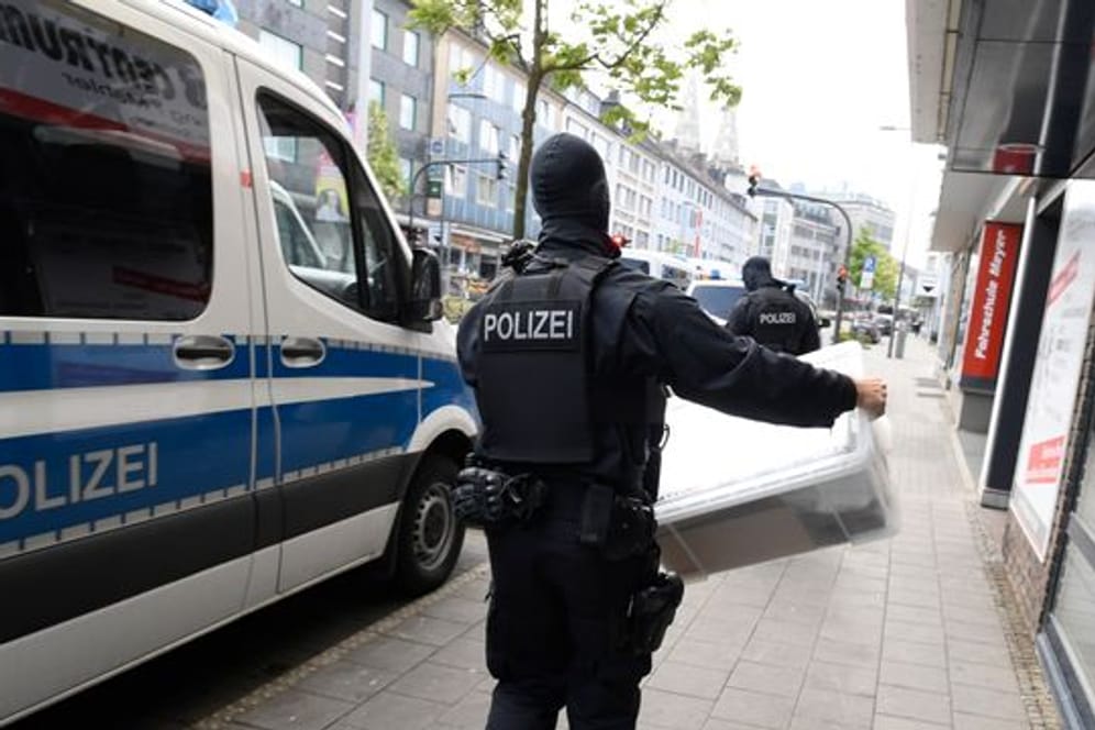 Ein Polizist trägt eine Kiste aus einem Gebäude, die die Polizei bei einer Razzia gegen Clankriminalität fand.