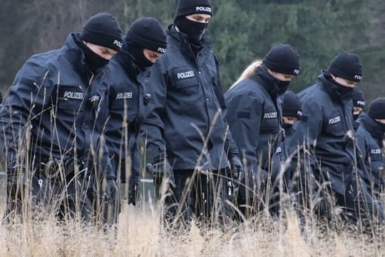 Polizeibeamte suchen auf einer Wiese Spuren, nachdem in der Nähe eine 16-Jährige tot aufgefunden worden ist.
