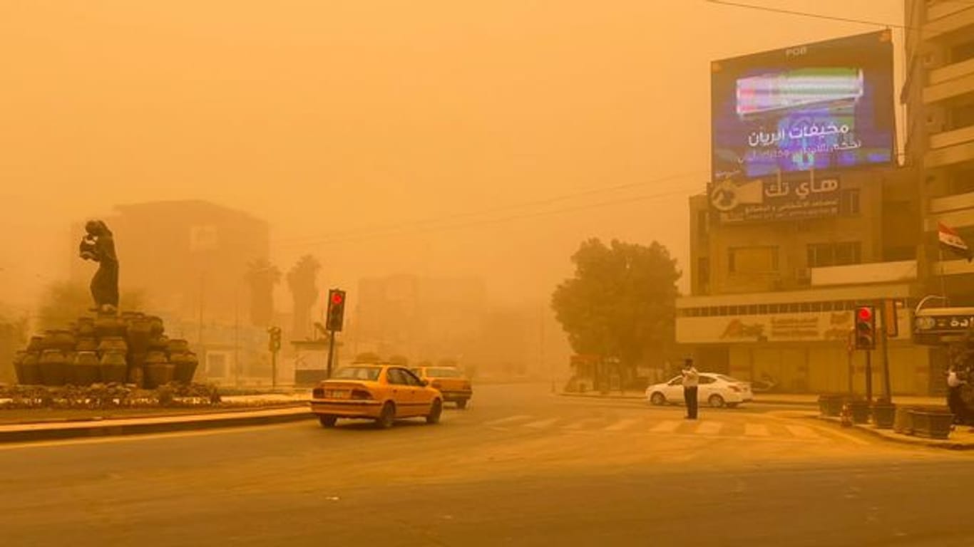 Autos in Bagdad fahren durch einen Sandsturm.