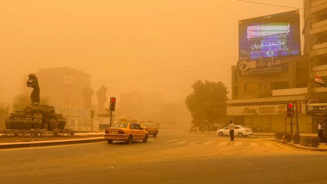 Autos in Bagdad fahren durch einen Sandsturm.