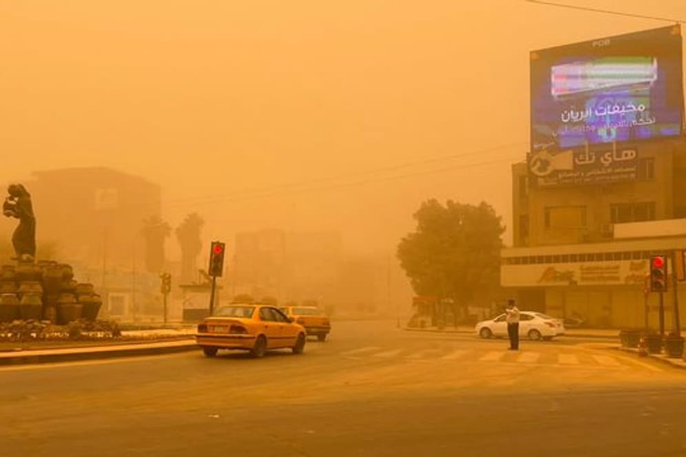 Autos in Bagdad fahren durch einen Sandsturm.