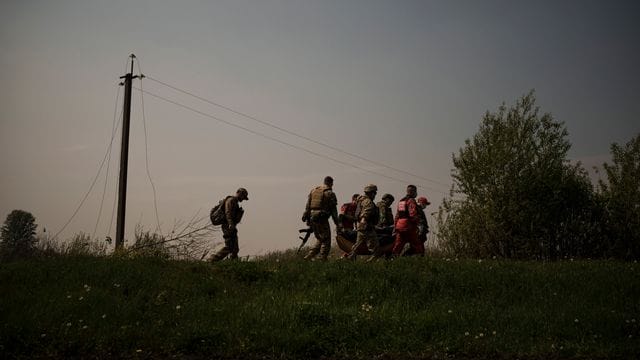 Ukrainische Soldaten und Rettungskräfte tragen die Leiche eines mutmaßlichen russischen Soldaten.