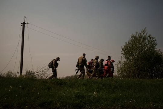 Ukrainische Soldaten und Rettungskräfte tragen die Leiche eines mutmaßlichen russischen Soldaten.